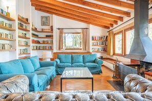A cozy living room with wooden beams, a fireplace, and bookshelves filled with books. - Chalet 'Ses Llebres' with Private Pool, Wi-Fi and Air Conditioning (Bunyola)