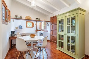 A kitchen with a dining table, chairs, a cabinet, and various kitchen appliances. - Chalet 'Ses Llebres' with Private Pool, Wi-Fi and Air Conditioning (Bunyola)