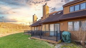 Une maison à deux étages dotée d’un patio couvert, de grandes fenêtres et de cheminées.
