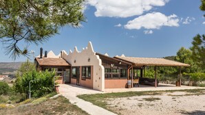 Un bâtiment doté d’une architecture originale, d’un espace extérieur aménagé avec des sièges et abrité, et d’un chemin de gravier menant à l’entrée.
