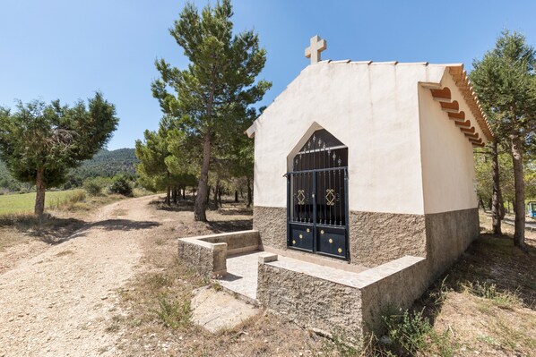 Un petit bâtiment d’un seul étage, surmonté d’une croix, avec une porte noire et des marches menant à l’entrée.