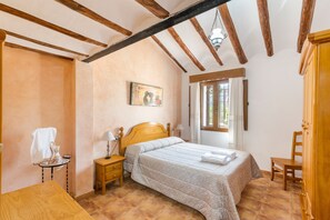 A bedroom with a wooden bed, a nightstand, a chair, a wardrobe, and a window with curtains.