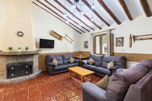 A living room with a fireplace, sofas, a coffee table, and a TV mounted on the wall.