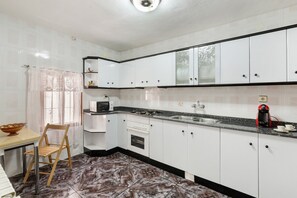 A kitchen with white cabinets, a microwave, a stove, a sink, and a coffee maker. - Apartment 'Villacalar Il' with Mountain View, Private Garden and Wi-Fi (Calar de la Santa)