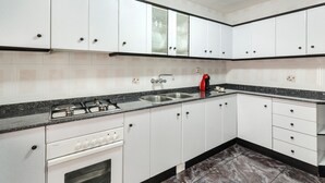 A kitchen with white cabinets, a gas stove, a sink, and a red kettle. - Apartment 'Villacalar Il' with Mountain View, Private Garden and Wi-Fi (Calar de la Santa)