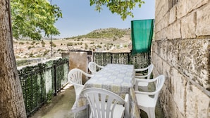 An outdoor patio with a table and chairs, a stone wall, and a view of a hilly landscape. - Apartment 'Villacalar Ill' with Mountain View, Private Terrace and Wi-Fi (Calar de la Santa)