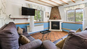 A living room with a sofa, fireplace, television, and windows. - Apartment 'Villacalar Ill' with Mountain View, Private Terrace and Wi-Fi (Calar de la Santa)