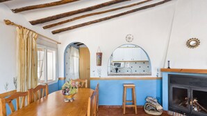 Un comedor con una mesa y sillas de madera, una cocina con estufa y una chimenea.