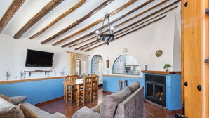 Una sala de estar con sofá, televisión, chimenea y un área de cocina con mostrador y armarios.