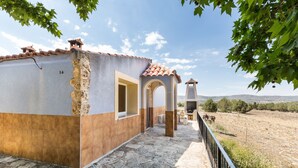 Un edificio con fachada de piedra, tejado de tejas y vistas al campo.