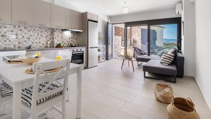 Uma cozinha moderna com área de refeições, uma varanda com sofá e vista para o mar.