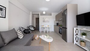 Uma sala de estar moderna com um sofá, uma mesa de centro e uma TV em um móvel.
