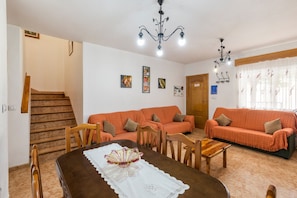 A dining area with a wooden table, chairs, and a chandelier. There is a staircase leading to another room. - Apartment 'Duplex Rural' with Mountain View, Private Terrace and Wi-Fi (Calar de la Santa)