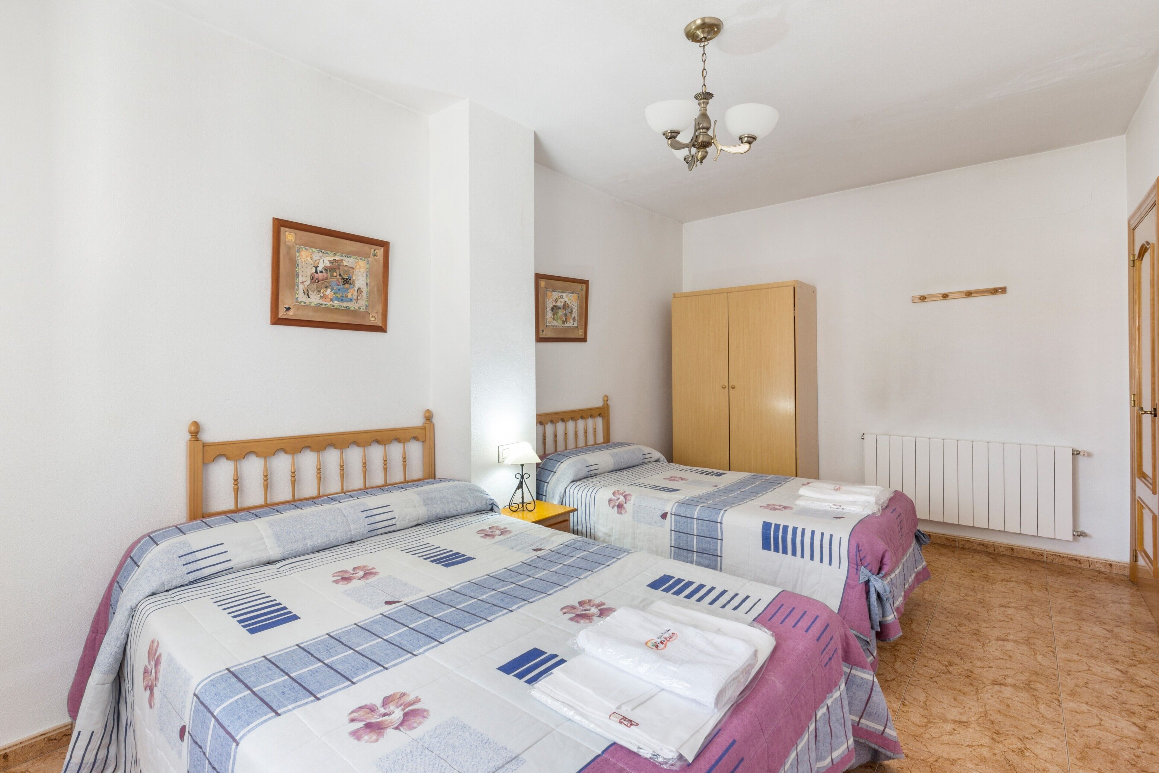 A bedroom with two beds, a wooden wardrobe, and a radiator.