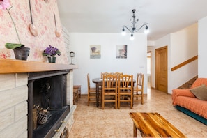 A living room with a fireplace, wooden dining table, and chairs, a sofa, and a chandelier. - Apartment 'Duplex Rural' with Mountain View, Private Terrace and Wi-Fi (Calar de la Santa)