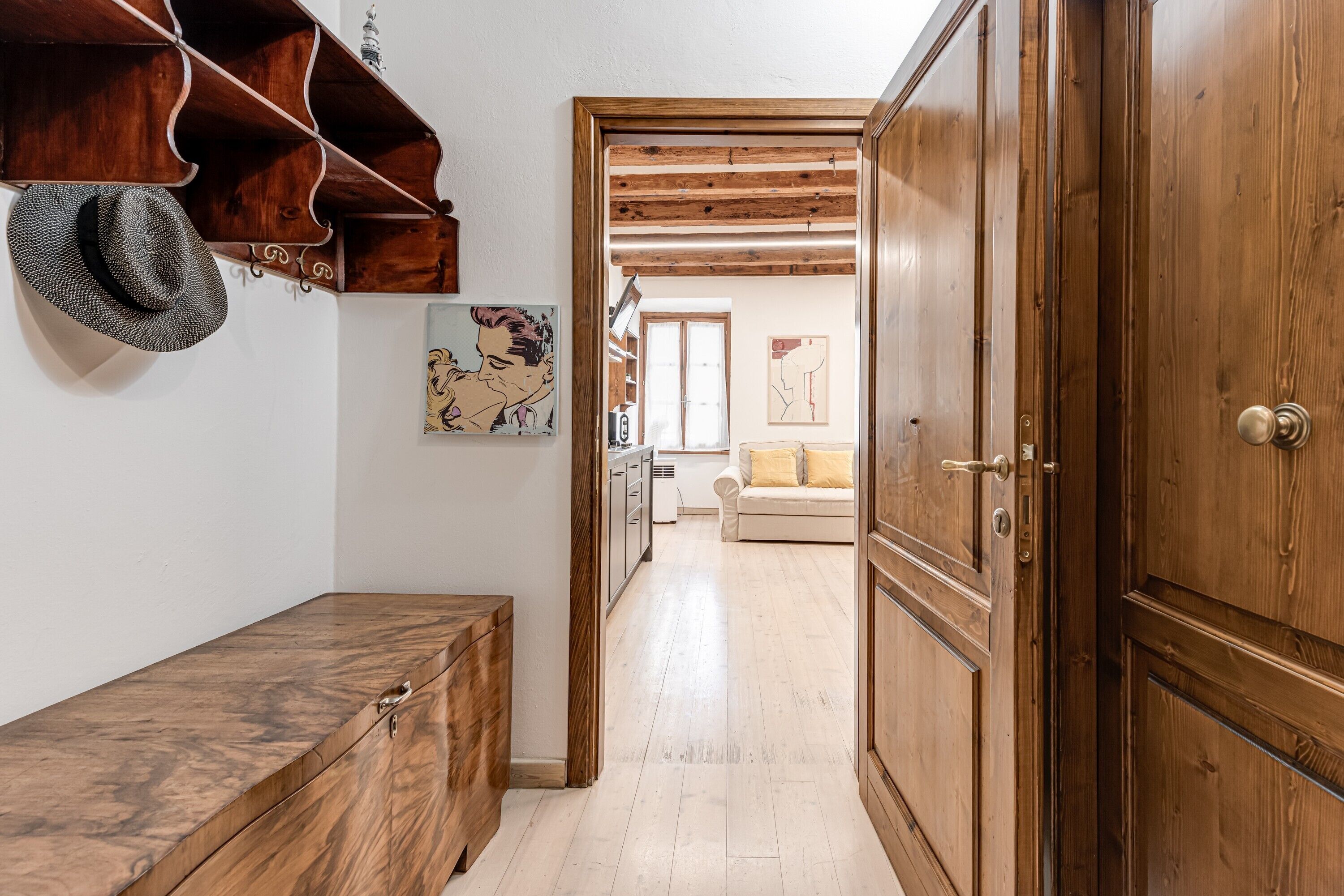 A hallway with wooden cabinets, a bench, and a door leading to another room.