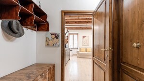 Un pasillo con armarios de madera, un banco y una puerta que da a otra habitación.