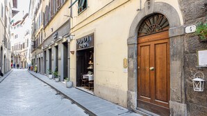 Una calle estrecha con edificios, una puerta de madera y un muro de piedra.