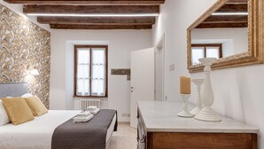 Un dormitorio con cama, mesita de noche, cómoda y un espejo grande.