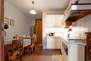 A kitchen with white cabinets, a microwave, a stove, and a dining area with chairs and a table.