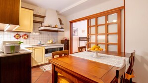 A kitchen with a wooden table, chairs, a stove, and a refrigerator.