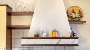 A kitchen with a marble countertop, a wooden shelf with vases, and a decorative plate.
