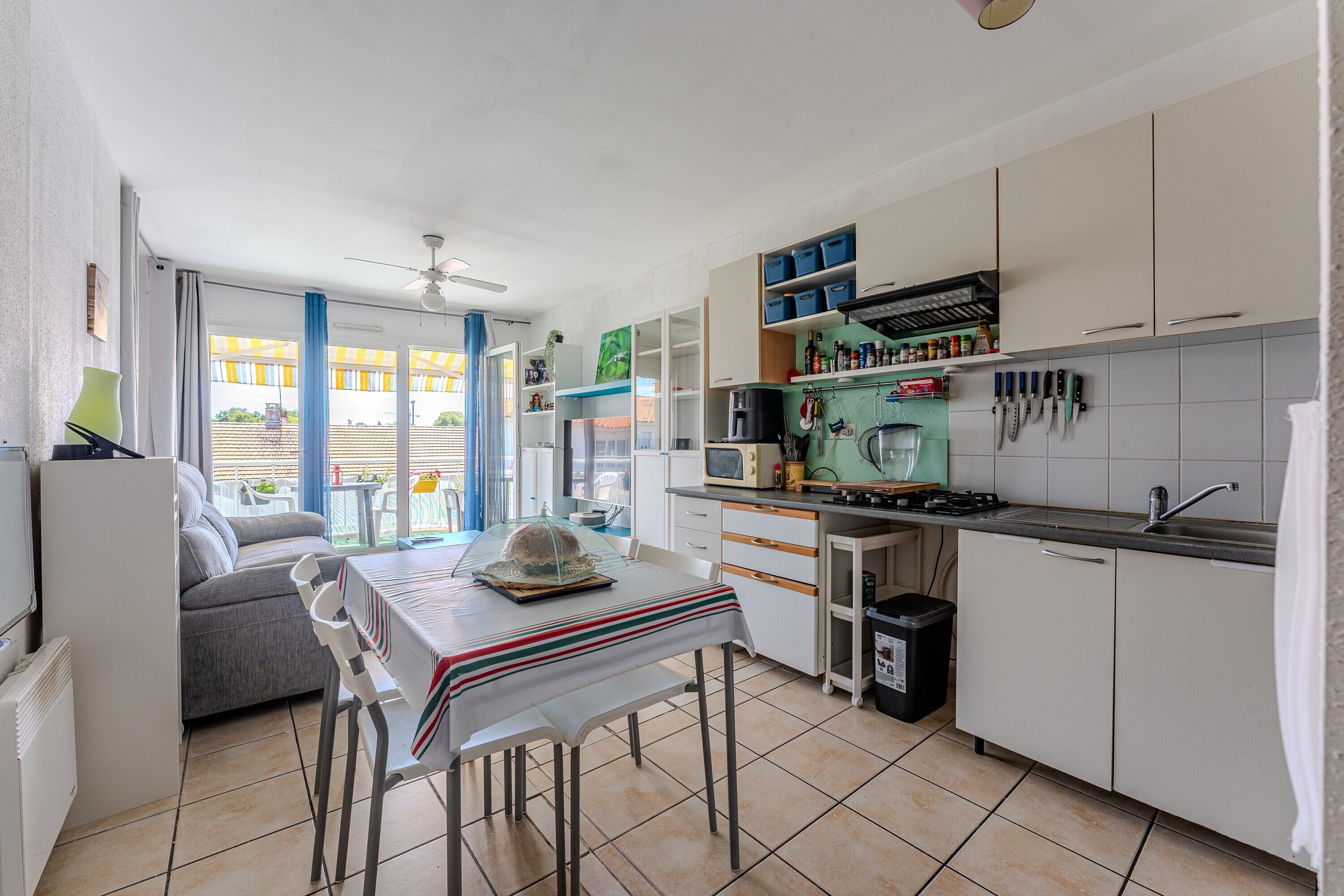 A compact kitchen with a dining area, white cabinets, a microwave, and a ceiling fan.