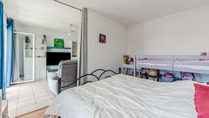 Un dormitorio con cama, escritorio, silla, armario y televisor.