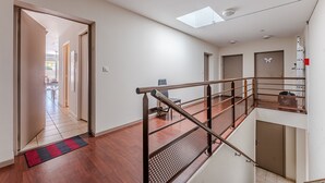Un interior espacioso con una escalera, vistas a un balcón y una puerta que conduce a otra habitación.