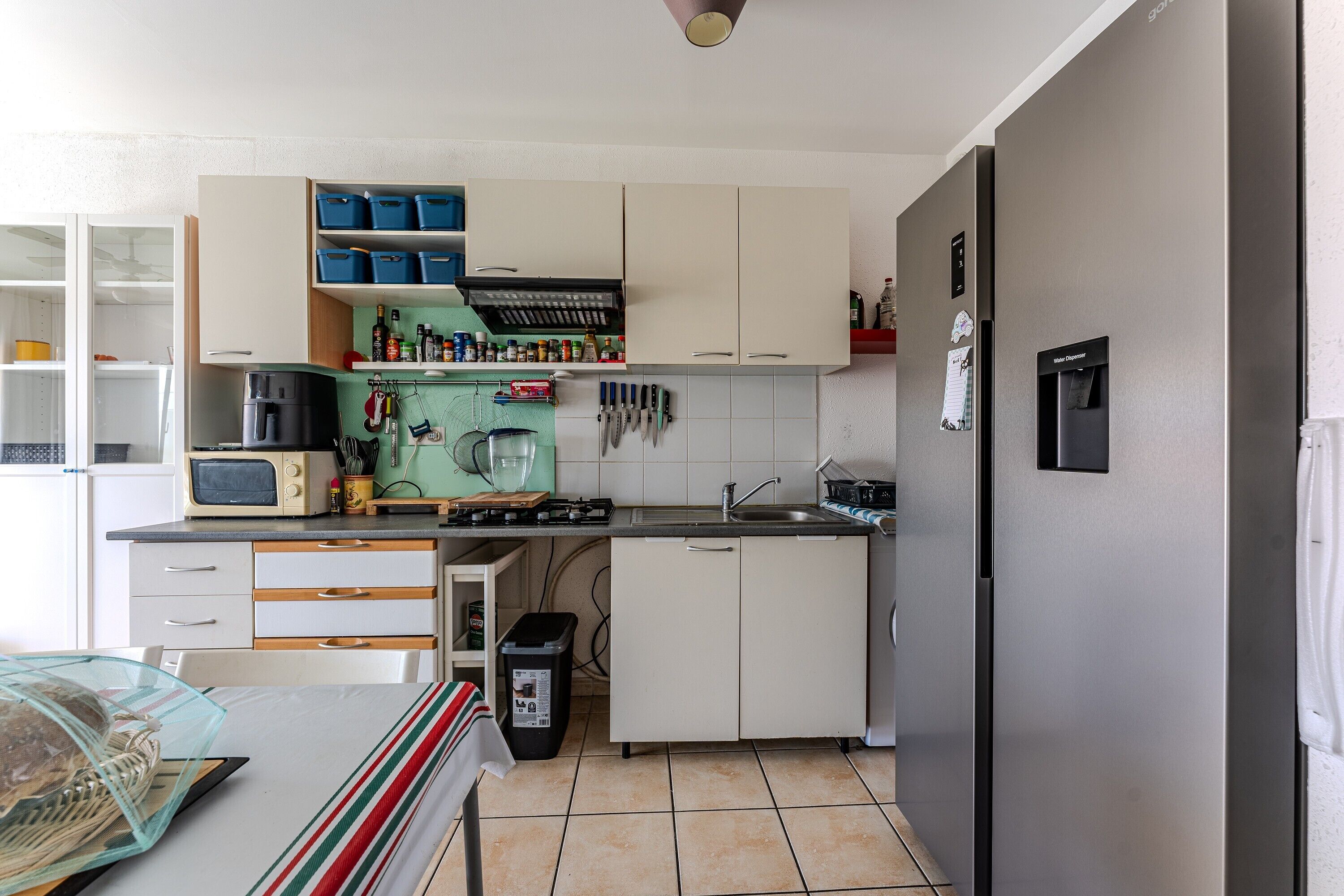 A compact kitchen with white cabinets, a microwave, a sink, and a refrigerator.