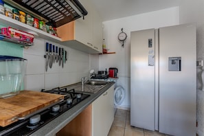 Cocina compacta con estufa a gas, lavamanos y refrigerador.