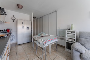 Una cocina compacta con refrigerador, estufa y comedor.