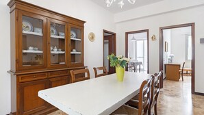 Ein Esszimmer mit einem großen Holzkabinett, einem weißen Tisch und Stühlen.