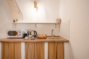 Uma cozinha compacta equipada com micro-ondas, cafeteira, chaleira e pia.