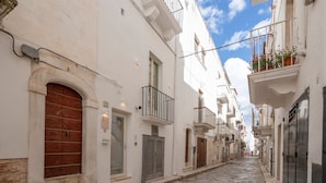 A narrow street with white buildings, a stone pavement, and a clear sky. - Apartment 'Perla' with Private Terrace and Optional SPA in Castellana Grotte (Castellana Grotte)