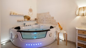 A modern bathroom with a freestanding bathtub, a small table with a bottle, and decorative wall shelves. - Apartment 'Perla' with Private Terrace and Optional SPA in Castellana Grotte (Castellana Grotte)