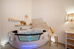 Une salle de bain moderne avec une baignoire sur pieds, une petite table avec une bouteille et des étagères murales décoratives.