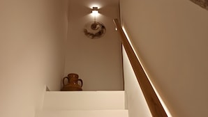 A staircase with white walls, a wooden handrail, and a wall-mounted light fixture. - Apartment 'Perla' with Private Terrace and Optional SPA in Castellana Grotte (Castellana Grotte)