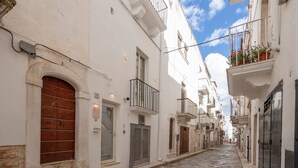 A narrow street with white buildings, a stone pavement, and a clear sky. - 'Ambra' Room with Balcony (Castellana Grotte)