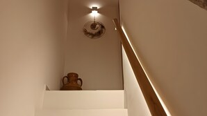 A staircase with white walls, a wooden handrail, and a wall-mounted light fixture. - 'Ambra' Room with Balcony (Castellana Grotte)