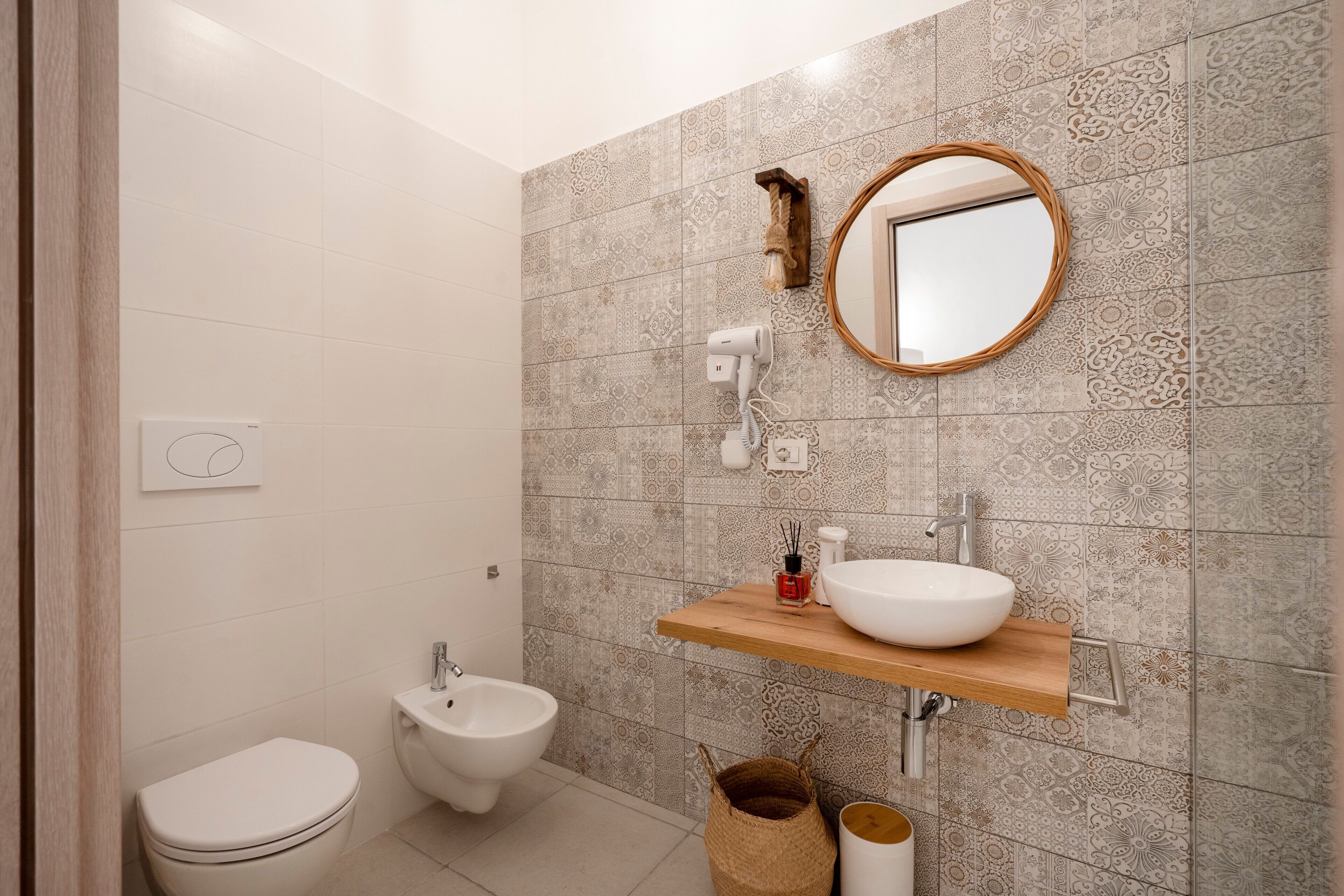 Une salle de bain comprenant des toilettes, un bidet, un meuble-lavabo et un miroir.