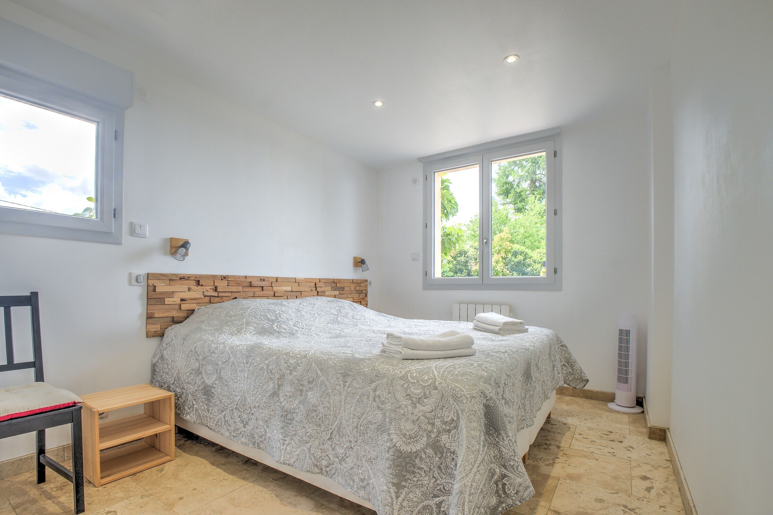 Ein Schlafzimmer mit Bett, Nachttisch, Fenster und Heizkörper.