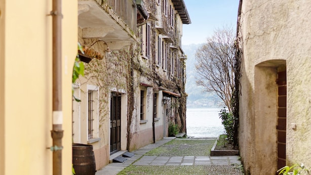 A narrow alleyway with buildings on either side, a stone pathway, and a view of a body of water in the distance. - Apartment 'Antro Di Circe - Orta Centro' with Private Terrace, Garden and Wi-Fi (Orta San Giulio)