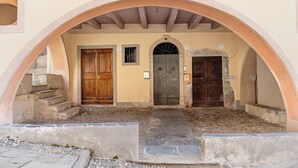 An arched entrance with three doors, a stone staircase, and a cobblestone path. - Apartment 'Antro Di Circe - Orta Centro' with Private Terrace, Garden and Wi-Fi (Orta San Giulio)
