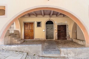 Un ingresso ad arco con tre porte, una scala in pietra e un sentiero acciottolato.