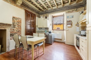 Cucina con parete in mattoni, mobili in legno, tavolo da pranzo con sedie, una finestra e un forno a microonde.