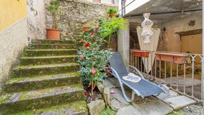 A narrow outdoor staircase with moss, a chair, and potted plants. - Apartment 'Antro Di Circe - Orta Centro' with Private Terrace, Garden and Wi-Fi (Orta San Giulio)