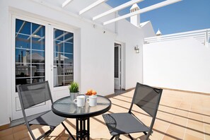 A patio with a round table, two chairs, a potted plant, and a bowl of fruit. - Holiday Apartment 'Casita Sabrina, Seaview Terrace' with Private Terrace and Wi-Fi (Playa Honda)