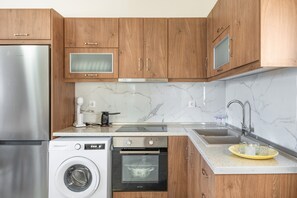 Una cocina moderna con armarios de madera, electrodomésticos de acero inoxidable, salpicadero de mármol y un lavamanos.