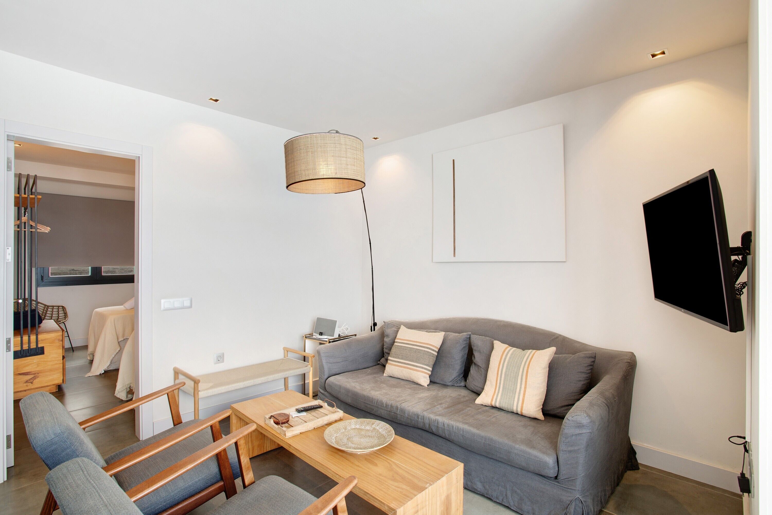 Un salon moderne avec un canapé, une table à manger et un téléviseur fixé au mur.